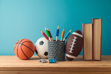Back to school concept with pencils, basketball ball, football ball and books on wooden table over blue background - 615654369