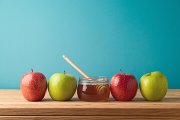 Honey jar and apples on wooden table over blue background. Jewish holiday Rosh Hashanah concept