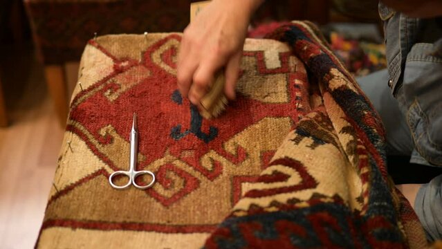 Woman restoring an Antique Oriental Rug. Brushing and cleaning the rug.