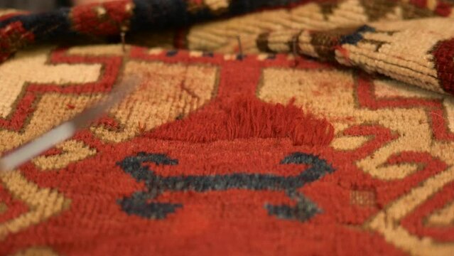Woman restoring an Antique Oriental Rug. Cutting the new knots to size.