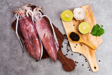 Fresh raw octopus on wooden chopping board background Seafood squid with lemon top view and copy...