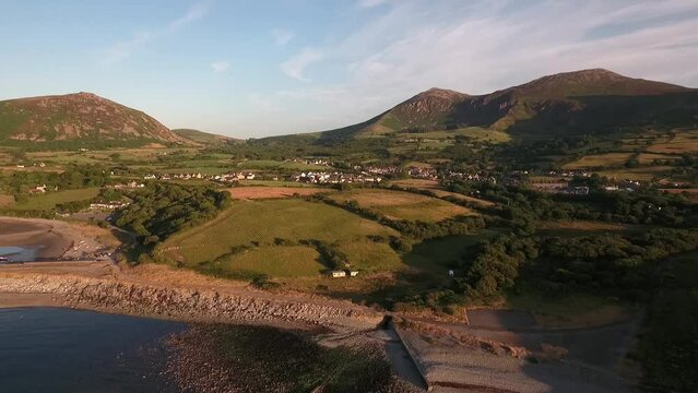 Aerial approach to Trefor  harbour and village over the beach and pier with blue skies on a summers day across the Irish Sea on the Llyn Peninsula in North Wales
