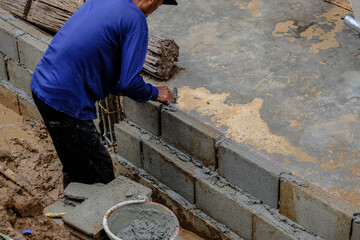 Mechanical man working on brick wall building with metal poll