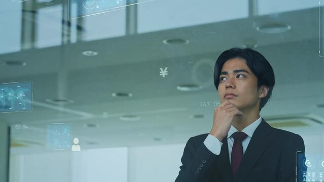 ガラスに映るデジタルデータを眺める男性
