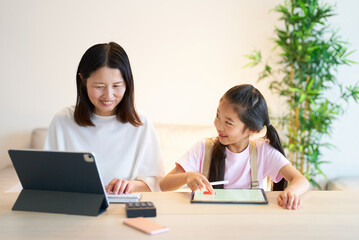 Obraz premium タブレットPCを使って仕事をする女性と遊ぶ女の子