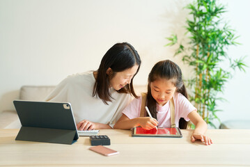 Naklejka premium タブレットPCを使って仕事をする女性と遊ぶ女の子