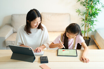 Obraz premium タブレットPCを使って仕事をする女性と遊ぶ女の子