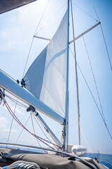 Yacht sailing in an open sea. Close-up view of sails of a sailing yacht in the wind and clear sky with sun