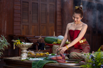 Asian women wearing Thai traditional Lanna style dresses cooking Thai traditional food in the Thai ancient house Chiang Mai, Thailand. Thai women is providing ingredients for cooking. Thai cultural - Powered by Adobe