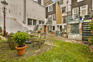 a back yard with some plants and pots on the ground in front of an apartment building that is being used as a garden