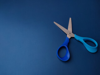Closeup blue scissors on a blue background