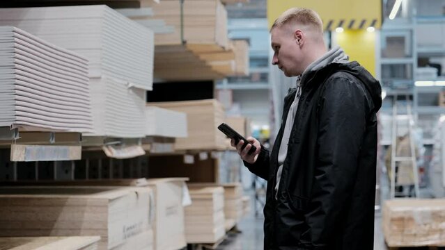 A man in a hardware store chooses building materials. A buyer buys plywood at a hardware store. Blockboards in a hardware store. Translation: good price