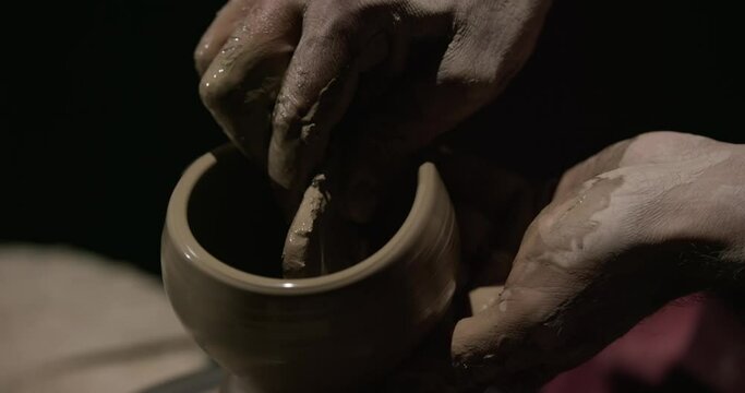 Hands of a master potter working on a potter's wheel in the manufacture of dishes