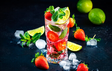 Summer strawberry mojito cocktail with lime, white rum, soda, cane sugar, mint, and ice in glass on deep blue background. Cold refreshing beverage