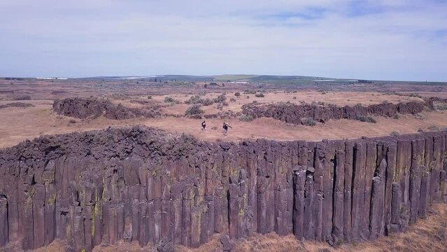 Establishing shot: Photographers carry cameras atop tall rock columns