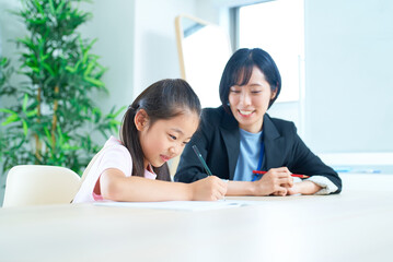勉強する女の子とサポートするスーツ姿の女性