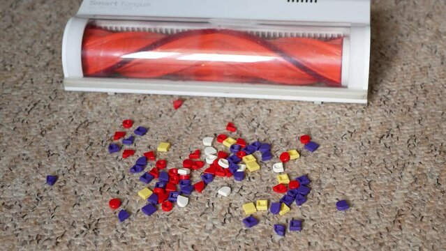 Working vacuum cleaner stops because of an obstacle in the form of small details of a plastic kids mosaic strewn on the floor. Cleaning in the children's room