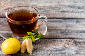 Close up shot of black tea with mint leaves,lemon, ginger slices with defocused background.