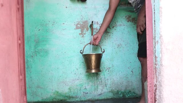 man filling his bucket with tap water in rural village