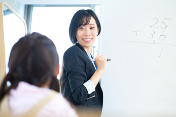 子どもに向かって授業するスーツ姿の女性