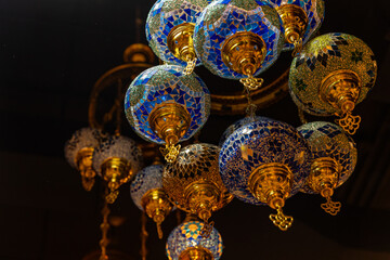 Dubai, Deira, United Arab Emirates - April 2023: Old tradional oil lamps hanging on the ceiling. Glass colored in blue and green.