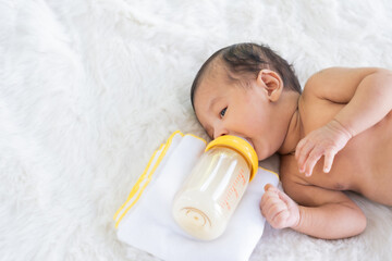 Babies on a white prom bed are sucking milk in a bottle. - 615692596