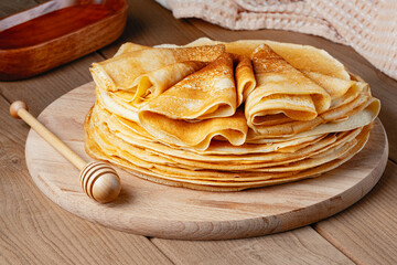 Thin pancakes on a wood plate. Homemade crepes, tasty food. Staple of yeast pancakes, traditional for Russian pancake week (Shrove tide). Thin pancake with crispy crust