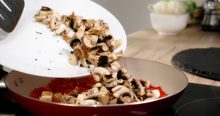 chopped mushrooms are added to the paprika in the pan and stirred with a spatula. cooking in the...