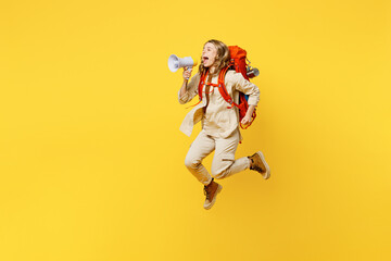 Fototapeta na wymiar Full body side profile view young woman carrying bag with stuff mat jump high scream in megaphone isolated on plain yellow background. Tourist walk on spare time. Hiking trek rest travel trip concept.