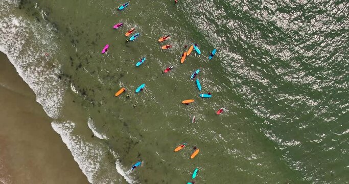 A beach with a surfing school practising on the waves by the shore 4k