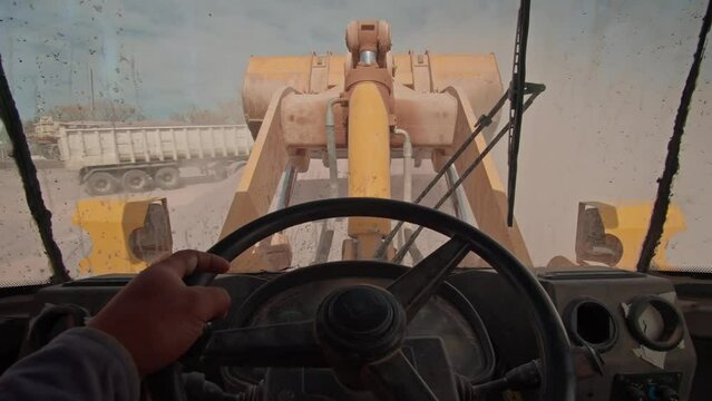 point of view of a bulldozer driver inside the cab while operating the mechanical shovel in a  stone quarry