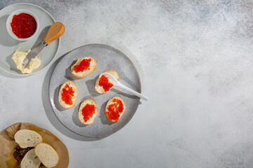 Sandwiches with red caviar. Bread, butter and red caviar  on gray background. Top view, copy space.