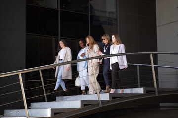 Successful female executives in formal attire walking out of office building at end of workday