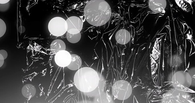 Animation of grey and white bokeh light spots moving over transparent sheets, films and bubble wrap