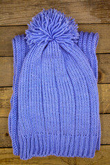 Handmade wool knitted winter blue hat and scrarf on wooden background