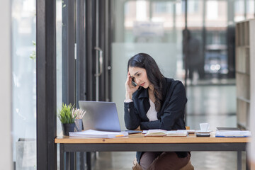 Portrait of tired young business Asian woman work with documents tax laptop computer in office. Sad, unhappy, Worried, Depression, or employee life stress concept	