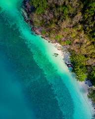 Fototapeta na wymiar Aerial view, top view, amazing nature background. The water colors are beautiful and bright. Azure beach with rocky mountains and clear ocean water of Thailand on a sunny day. Landscape background