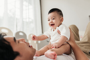 Asian adorable baby in a good mood, Enjoy playing with father. Father holding little baby and...