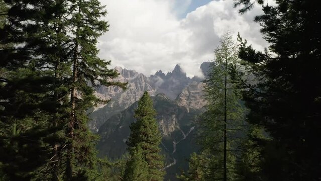 Unveil the majestic mountains of Monte Cristallo near Cortina d'Ampezzo as the drone weaves through trees, capturing the breathtaking cinematic aerial footage of the mountains. LuPa Creative.