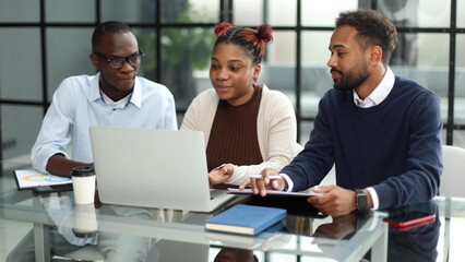 African american business team talking about strategy while looking at laptop, in office