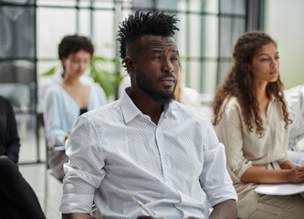 A close-up of sitting in a board room, making notes.