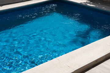 Waterproof case with money and a smartphone on the background of the pool on a sunny summer day.