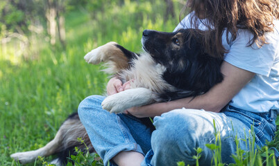 Young happy woman enjoying a summer day with her dog sitting in the garden on green grass