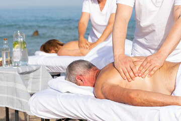 Family – man and woman having relax in tropical massage spa on the beach near the sea on massage...