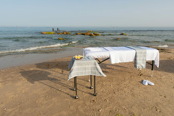Massage table on the beach near the sea prepared by professional masseur for relax in tropical massage spa procedures.