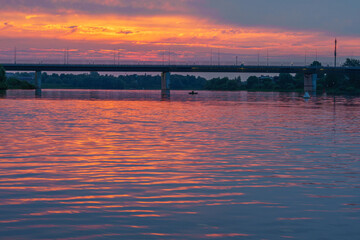 Obraz premium Beautiful summer sunrise over the river. The bridge against the background of the sunrise on a summer morning.