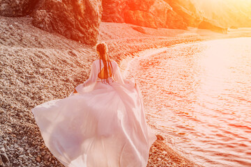 Mysterious woman silhouette long hair walks on the beach ocean water, sea nymph wind listens to the...