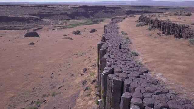 Hiker walks atop dramatic volcanic basalt rock columns in WA state