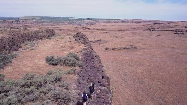 Basalt columns: Photographers carry camera gear along arid cliff top