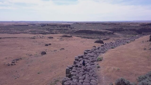 Aerial view: Hiker walks atop basalt rock columns in Scablands of WA